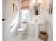 Stylish half-bath with white pedestal sink, toilet, and sunny window with woven shade at 3567 Somerset Hills Ct, Mount Pleasant, SC 29466