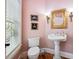 Charming powder room features a pedestal sink, decorative mirror, and soft lighting with pink walls at 4386 Park Island Rd, Hollywood, SC 29449