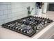 Close-up of a modern gas cooktop with stainless steel knobs and white subway tile backsplash at 5005 Buckland Trl, Ridgeville, SC 29472
