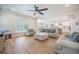 Open-concept living room featuring hardwood floors, neutral-colored sofas, ceiling fan, and a view of the kitchen at 5005 Buckland Trl, Ridgeville, SC 29472
