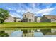 Back exterior view of home with a screened-in porch and a lush green lawn, reflected in the lake at 515 Flycatcher Dr, Goose Creek, SC 29445