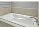 A crisp white bathtub is surrounded by neutral-toned tiling at 5554 Colonial Chatsworth Cir, North Charleston, SC 29418