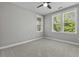 Bright bedroom with neutral carpet, fan, and three windows, bringing the outside in at 5554 Colonial Chatsworth Cir, North Charleston, SC 29418