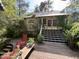 Charming front porch with wooden deck, stairs, and a cozy red rocking chair surrounded by lush greenery at 815 W Carolina Rd, McClellanville, SC 29458