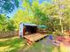 Backyard shed with an open deck, picnic table, umbrella, and fire pit area surrounded by lush trees at 816 Savage Rd, Charleston, SC 29414