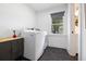 Convenient laundry room features modern washer, dryer, cabinet, window, and dark geometric tiled floors at 847 Condon Dr, James Island, SC 29412
