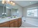 Bright bathroom with a double sink vanity, large mirror, soaking tub and neutral tile flooring at 9042 Parlor Dr, Ladson, SC 29456