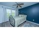 Bedroom with a navy blue accent wall, ceiling fan, and a large window with light-filtering curtains at 9042 Parlor Dr, Ladson, SC 29456
