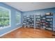 Bright, blue living room featuring hardwood floors and shelving units with books and collectables by the windows at 9042 Parlor Dr, Ladson, SC 29456