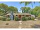 Charming brick home with a well-manicured front yard, mature trees, and a welcoming red front door at 1012 Cliffwood Dr, Mount Pleasant, SC 29464