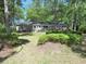 Brick home nestled among trees, featuring a well-maintained lawn and a serene backyard at 1527 S Pinebark Ln, Charleston, SC 29407