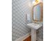The powder room features a white pedestal sink, statement mirror, and patterned wallpaper at 155 Wingo Way # 415, Mount Pleasant, SC 29464