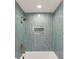 A bathroom with a teal tiled shower and gold fixtures plus a built in shower caddy for storage at 193 Corn Planters St, Charleston, SC 29492