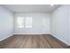 Bright, open living room with wood-look floors, two windows, white walls and a white door at 202 W Bradford Pointe Drive Dr, Summerville, SC 29483