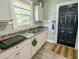 This kitchen has a stainless steel sink and white cabinets with gray counter tops and a black entry door at 2125 Victory Ave, North Charleston, SC 29405