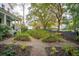 Landscaped garden with a gravel pathway, raised flower beds, and mature trees at 305 N Civitas St, Mount Pleasant, SC 29464