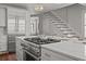 Close-up of modern kitchen island with gas range, stainless steel appliances, and staircase in background at 34 Pinckney St, Charleston, SC 29401
