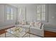 Comfortable living room with a gray couch, decorative pillows, and multiple windows with white shutters at 34 Pinckney St, Charleston, SC 29401