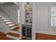 Modern wine nook featuring a wine fridge, marble countertop, and stylish shelving near staircase at 34 Pinckney St, Charleston, SC 29401