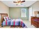Neutral-colored bedroom with ceiling fan, window, dresser, and bed with colorful patterned comforter and rug at 409 Thoroughbred Dr, Moncks Corner, SC 29461