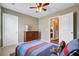 Neutral-colored bedroom with ceiling fan, window, dresser, and bed with colorful patterned comforter and rug at 409 Thoroughbred Dr, Moncks Corner, SC 29461