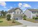 Side view of a home with a two-car garage, lawn, and lush landscaping at 409 Thoroughbred Dr, Moncks Corner, SC 29461