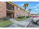 Brick condo building exterior with upper balconies, dark-shuttered windows, tropical landscaping, and parking at 415 Parkdale Dr # 2B, Charleston, SC 29414
