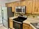Efficient kitchen featuring stainless steel appliances, tile flooring, and wood cabinets for ample storage at 5226 Fernland Way, North Charleston, SC 29420