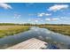Scenic pier view of marshlands, waterway, and cloudy sky at 5569 Frisco Ln, Johns Island, SC 29455
