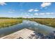Dock view overlooking a serene river and distant marshland, beneath a partly cloudy sky at 5569 Frisco Ln, Johns Island, SC 29455