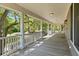 Spacious covered porch with white columns and wooden floors overlooking lush green trees and landscaping at 5569 Frisco Ln, Johns Island, SC 29455
