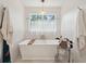 Bright bathroom featuring a soaking tub below a window and stylish neutral decor at 595 Crowned Kinglet Retreat, Charleston, SC 29412