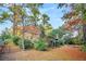 Landscaped backyard featuring a view of the brick house and mature trees at 7 Andrea Ct, Hanahan, SC 29410