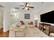 A bright living room with hardwood floors features a comfortable sectional sofa, ceiling fan, and a television at 853 Bibury Ct, Charleston, SC 29414