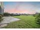 Large backyard featuring decorative stone patio, lush lawn, privacy fence, and neighborhood pond in view at 103 Radtko Rd, Summerville, SC 29486