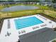 Aerial view of a rectangular pool with multiple chairs, surrounded by a lake and residential homes at 103 Radtko Rd, Summerville, SC 29486