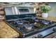 Close-up of a stainless steel gas stove top with granite countertops and mosaic tile backsplash in a modern kitchen at 103 Radtko Rd, Summerville, SC 29486