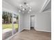 Bright dining room features modern light fixture, wood-look flooring, and sliding glass door to backyard at 108 Wadmalaw Cir, Summerville, SC 29483
