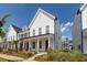 Charming two-story home featuring a covered front porch with brick accents, and landscaped yard at 119 Summer Tanager Dr, Ravenel, SC 29470