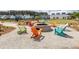Community fire pit with colorful adirondack chairs on a gravel ground, surrounded by a lawn and trees at 119 Summer Tanager Dr, Ravenel, SC 29470