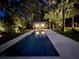 Resort-style backyard with a pool and cabana, beautifully landscaped and illuminated at night at 126 Sparrow Dr, Isle of Palms, SC 29451