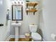 Well-appointed powder room with a pedestal sink, decorative mirror, and stylish shelving for added storage at 1426 Tannery Row, Johns Island, SC 29455