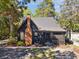 A charming home with dark siding and a brick chimney set on a lot with beautiful trees at 1456 Remount Rd, North Charleston, SC 29406