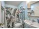 Functional bathroom with a toilet, sink, shower with a tropical curtain, and storage shelves at 172 Saint Philip St # F, Charleston, SC 29403