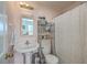 Compact bathroom with a pedestal sink, toilet, shower with curtain, and convenient shelving for storage at 172 Saint Philip St # F, Charleston, SC 29403