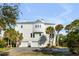 Spacious three-story white house with three car garage and palms gracing the yard at 23 Fairway Village Ln, Isle of Palms, SC 29451