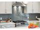 Close-up view of kitchen featuring stainless steel range and hood with tile backsplash and white countertops at 2815 Colonel Harrison Dr, Johns Island, SC 29455