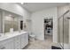 A well-lit bathroom featuring a double sink vanity, tiled floor, glass shower, and walk-in closet at 3431 Great Egret Dr, Johns Island, SC 29455