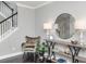 Stylish foyer showcasing a decorative table with a round mirror and comfortable chair near the staircase at 4906 W Liberty Park Cir, North Charleston, SC 29405