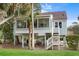 Stilt home with large windows, a deck, and stairs surrounded by lush landscaping at 507 Cobby Creek Ln, Seabrook Island, SC 29455